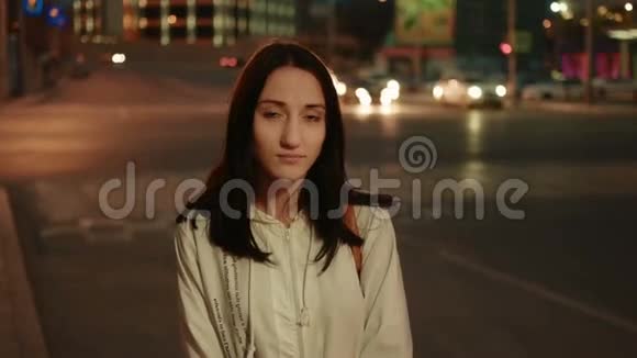 城市中的年轻女子晚上在模糊的车灯背景下严肃的面部肖像萼片色调视频的预览图