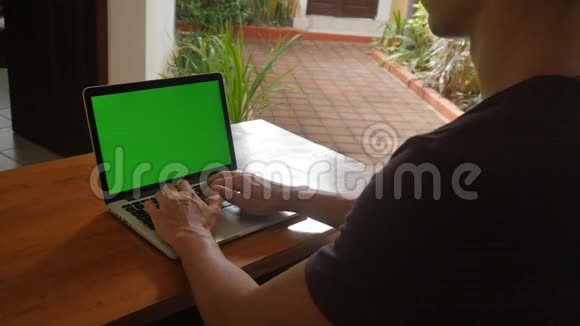 男人在家里用绿色屏幕在笔记本电脑工作自由职业者在家工作视频的预览图