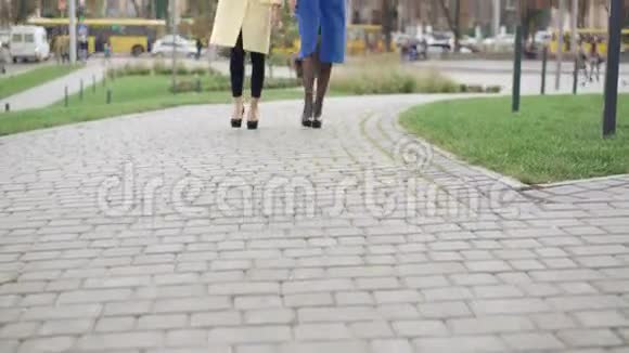 两个穿外套的女孩在人行道上行走的腿视频的预览图