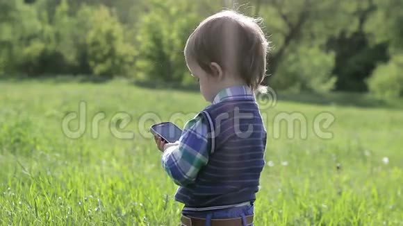 小男孩在大自然中玩电话视频的预览图
