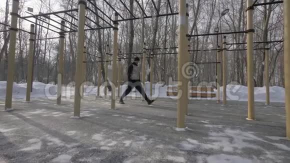 健身男子在冬季运动场户外做深蹲运动视频的预览图