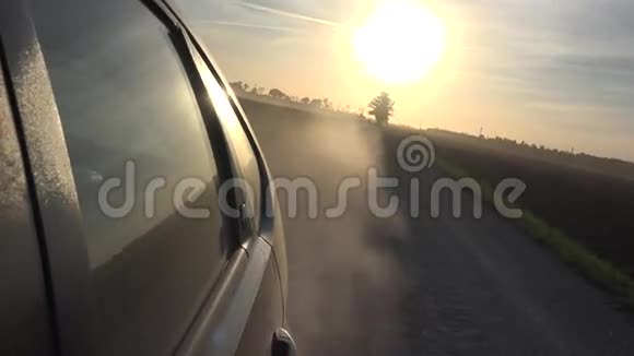 汽车车轮上的尘土飞扬汽车行驶在农村的碎石路上太阳在天空中4K视频的预览图