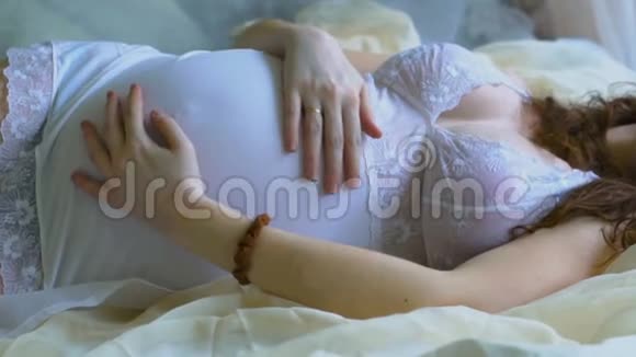 美丽的怀孕女孩躺在床上视频的预览图