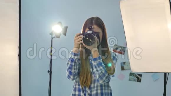 年轻的女摄影师配备专业摄影棚视频的预览图