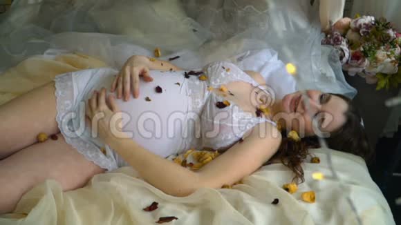 美丽的怀孕女孩躺在床上视频的预览图
