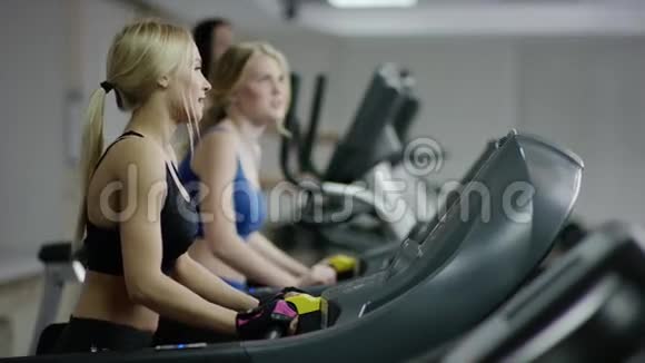 两个年轻的金发女人在跑步机上行走视频的预览图