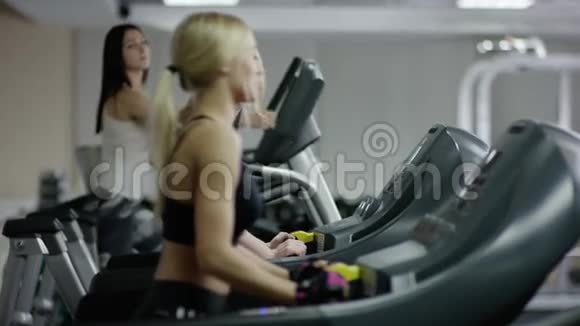 两个年轻的金发女人在跑步机上行走视频的预览图