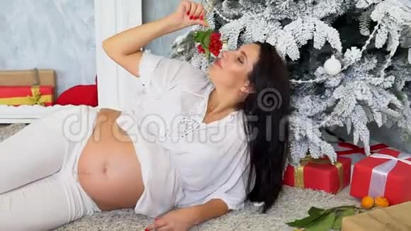 带着圣诞礼物在圣诞树旁怀孕的妈妈视频的预览图