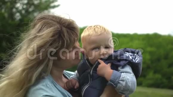 金发的年轻妈妈和宝宝在户外玩耍时一起笑视频的预览图