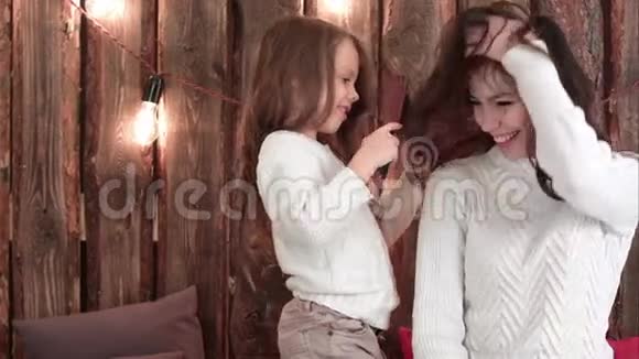 可爱的小女儿梳着深色头发的母亲坐在沙发上视频的预览图