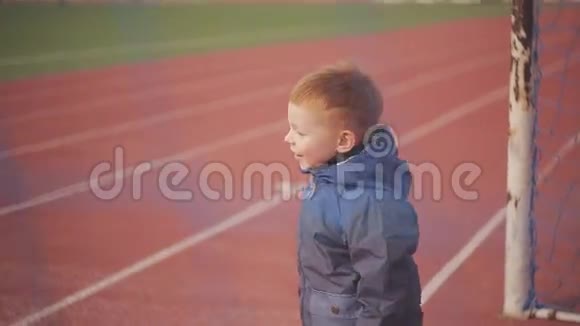 红头发的小男孩在体育场玩足球视频的预览图