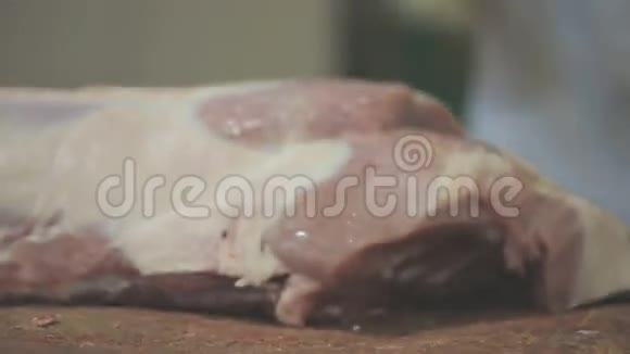 一个屠夫用斧头特写把猪肉胴体切成部分视频的预览图