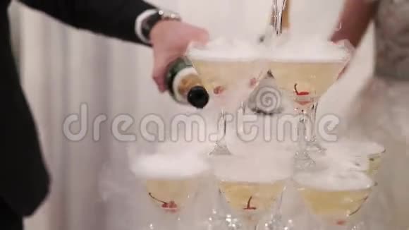 新郎新娘把香槟酒倒在玻璃金字塔上视频的预览图