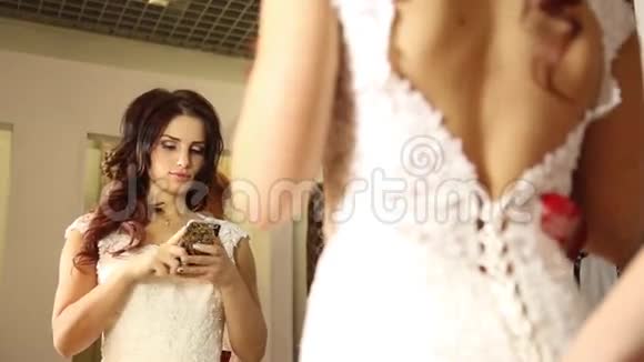 咨询师帮助年轻女性尝试婚纱女孩很高兴选择婚纱年轻新娘自拍视频的预览图