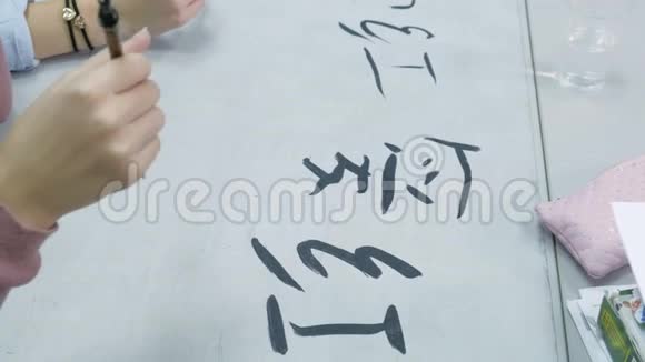 女子教青少年如何在书法课上写汉字学生用毛笔墨水和视频的预览图