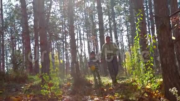 年轻的父子在秋天的森林里散步视频的预览图