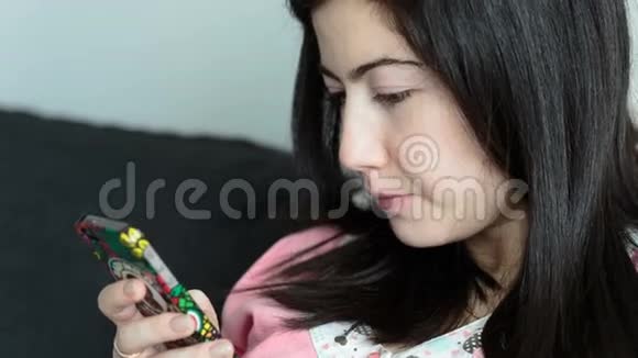 年轻的黑发女人在看你的智能手机视频的预览图