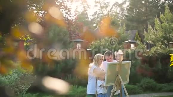 花园里画架上的年轻家庭画视频的预览图