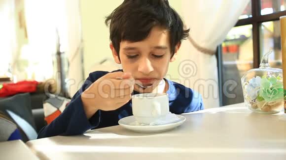 一个孩子在咖啡馆里用勺子喝热茶视频的预览图