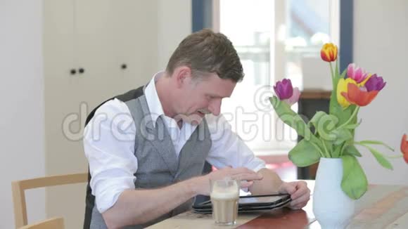 一个人坐在桌旁写着字对着镜头微笑视频的预览图