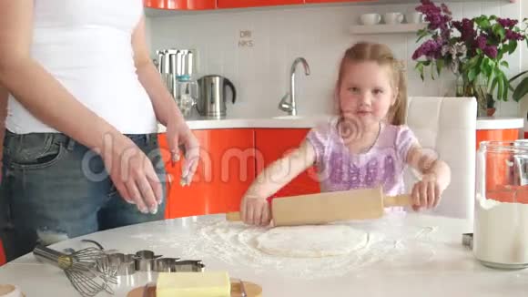 年轻漂亮的妈妈教女儿在厨房准备面团视频的预览图