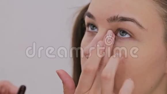 近距离射击化妆师将奶油底眼影底漆应用于模型眼视频的预览图