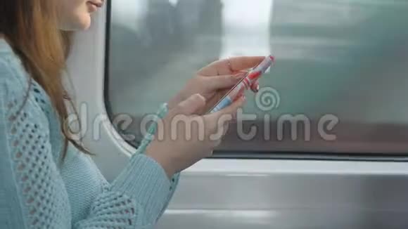 年轻女孩坐火车和使用手机漂亮的女人从智能手机上发送信息吸引力视频的预览图