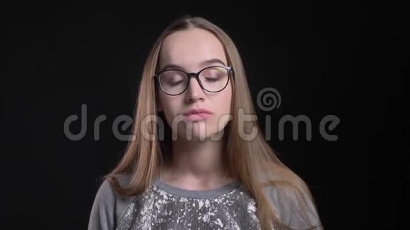 年轻迷人的时髦女性戴着眼镜直视镜头背景与黑色隔离视频的预览图