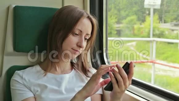 坐在火车上的有手机的年轻女子视频的预览图
