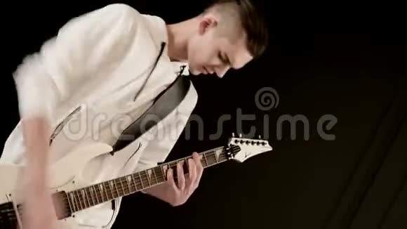 时尚的节奏吉他手不同的眼睛穿着白色的衣服在黑色的背景富有表现力地演奏白色视频的预览图