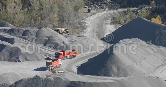 自卸卡车在花岗岩采石场行驶在采石场用重型机械开采石块视频的预览图
