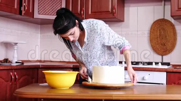 女人用抹刀将奶油用手抹在巧克力海绵蛋糕上视频的预览图