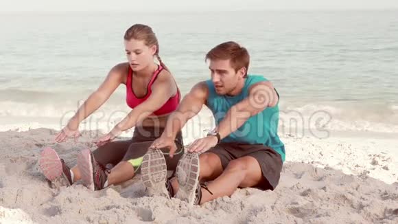 微笑的情侣在海滩上伸展双腿视频的预览图