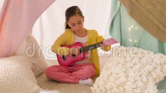 在家里的帐篷里玩玩具吉他的女孩视频的预览图