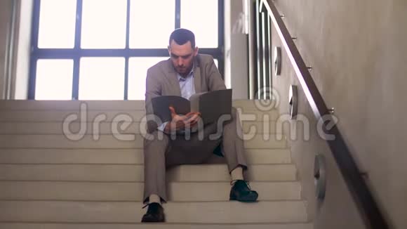 有文件夹的商人坐在楼梯上视频的预览图