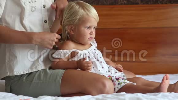 妈妈把小女儿的头发梳在沙发上视频的预览图