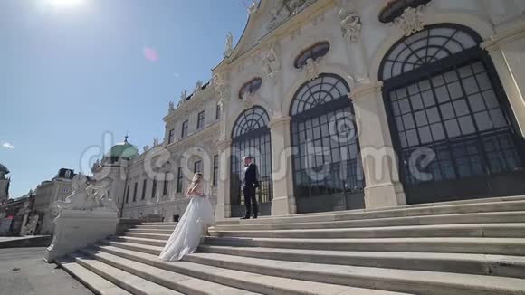 新郎和新娘站在Wiena大皇宫旁边的楼梯上视频的预览图