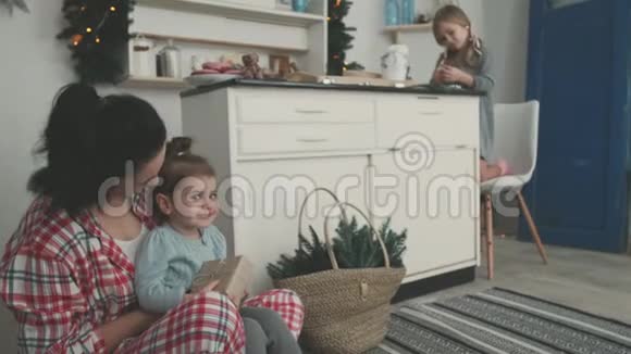 漂亮的年轻妈妈和她可爱的小女儿在厨房里烤饼干切割器微笑视频的预览图
