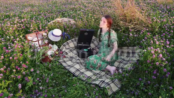 小女孩在草地上野餐听着老式留声机的唱片视频的预览图