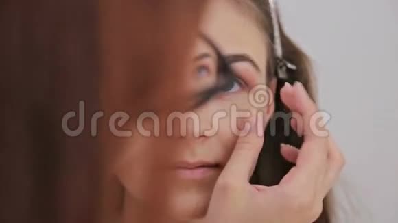近距离射击化妆师将奶油底眼影底漆应用于模型眼视频的预览图