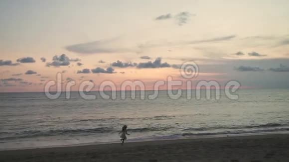 女孩沿着海滩奔跑享受日落视频的预览图