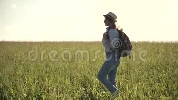 年轻的女游客去草地上戴着太阳镜帽子和背包的女旅行者视频的预览图