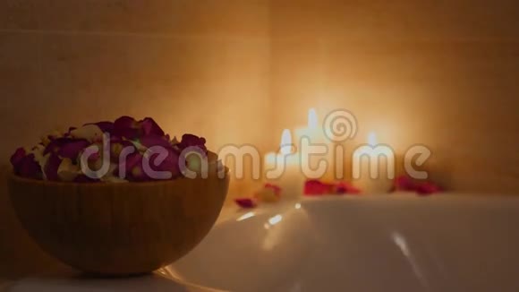 浴室花瓶中的玫瑰花瓣背景是燃烧的蜡烛4k视频的预览图