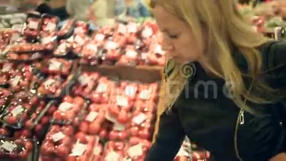 一个女人在蔬菜货架上的超市里买蔬菜和水果男人选择番茄视频的预览图