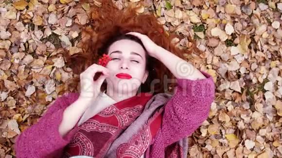 在秋天的森林里红色头发的美丽女孩在干燥的干燥的叶子在缓慢的运动中3840x2160视频的预览图