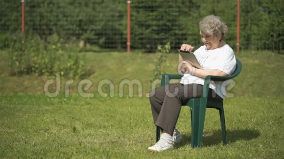 老妇人在户外拿着银色的电脑平板电脑视频的预览图