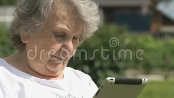 老妇人在户外拿着银色的电脑平板电脑视频的预览图