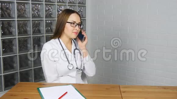 女医生坐在办公室里用智能手机视频的预览图