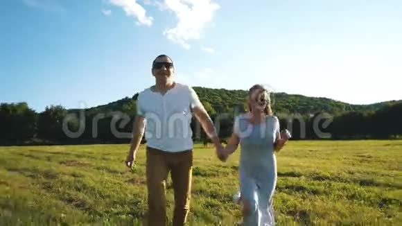 一对恋爱中的年轻夫妇牵着手跑过田野视频的预览图