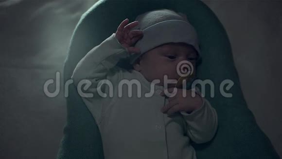 可爱的婴儿嘴里放着奶嘴躺在婴儿床上视频的预览图